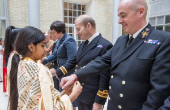 On August 28, local UK youth tie Rakhis on the wrists of British Army troops
